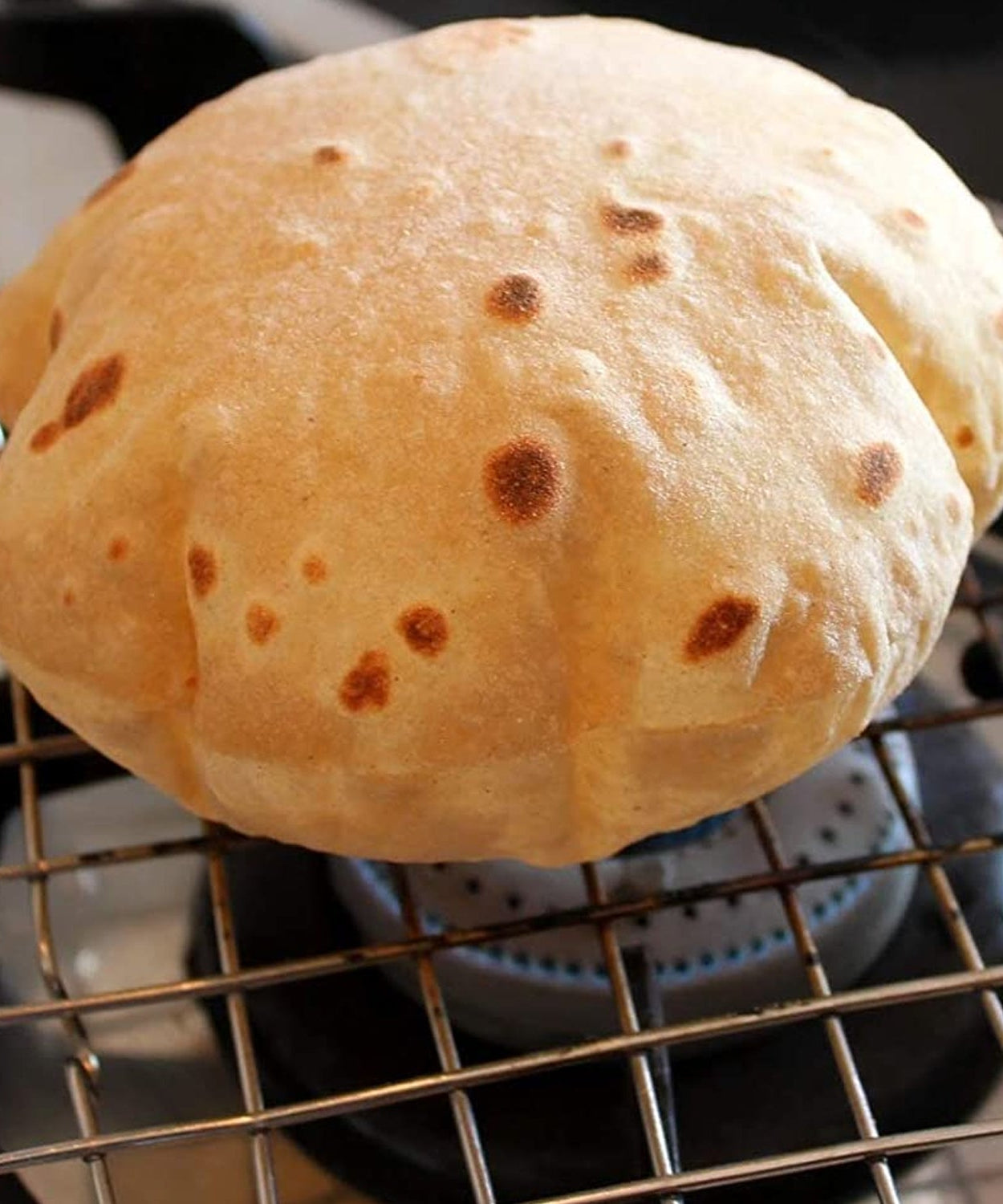 Kitchen grill with square stainless steel design and wooden handle.