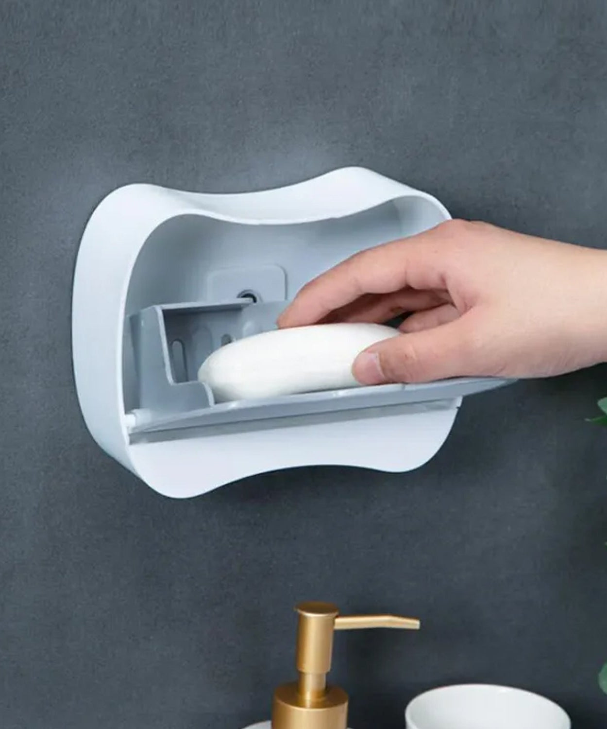 Close-up of wall-mounted soap box showing drain and flip-type lid.