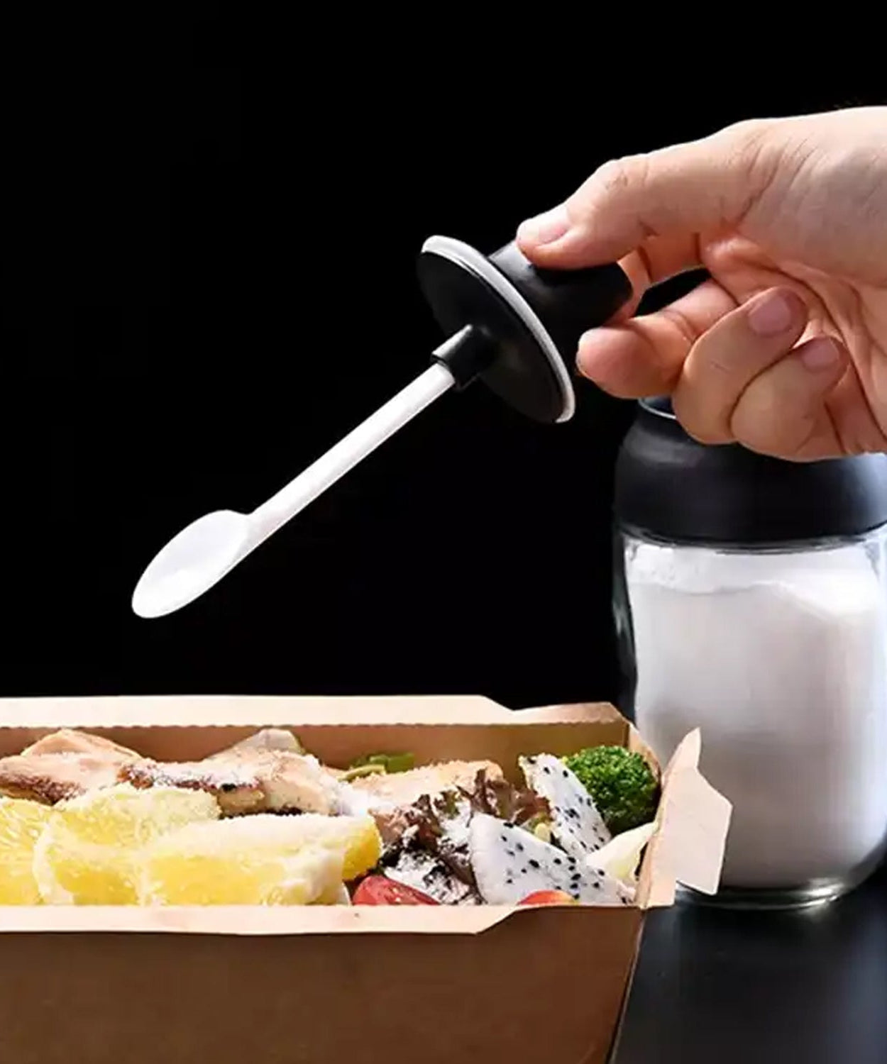 Heat-resistant glass seasoning jar with spoon for kitchen use.