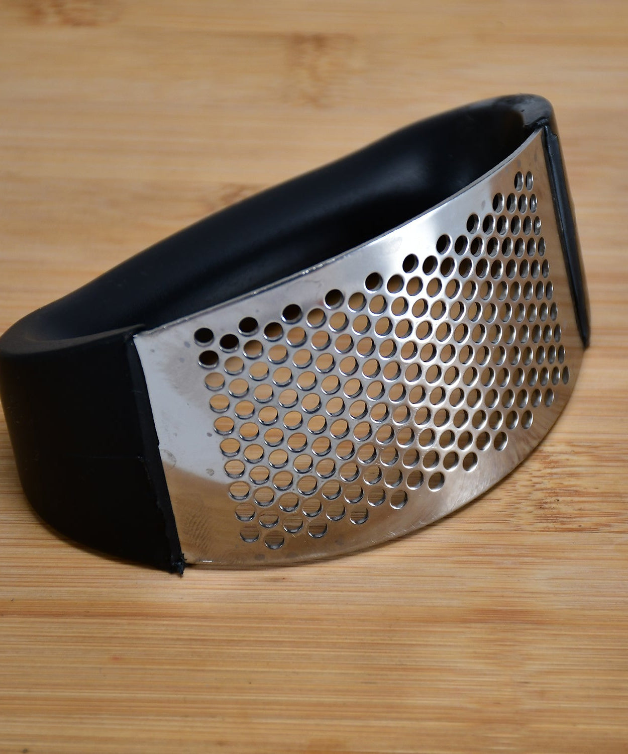 Stainless steel garlic crusher with ergonomic handle in multicolor.